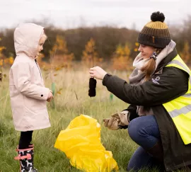 national forest employee hands young girl a sapling 