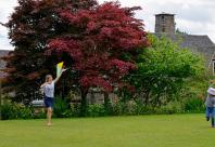 Photograph of an adult and child trying to fly a kite on a lawn